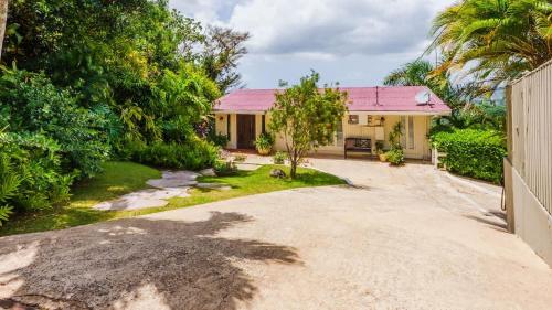 a house with a pink roof and a driveway at Chalet Lulu with Solar Power and Hot Tub in Guaynabo in Puerto Nuevo