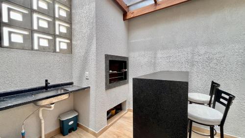 a room with a sink and a counter with two chairs at Casa pertinho do mar in Capão da Canoa