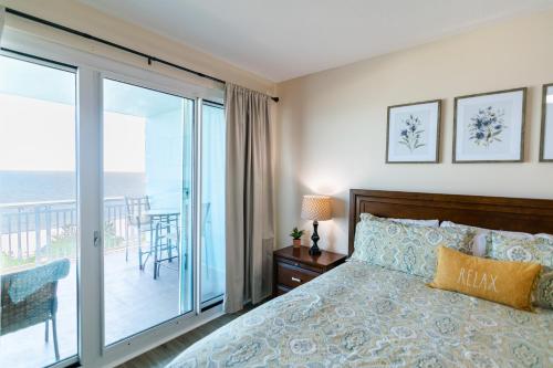 ein Schlafzimmer mit einem Bett und einem Balkon in der Unterkunft Beachview Condo in Legacy Tower 1 -603 - fully furnished 3 bedroom 2 bathroom in De Buys