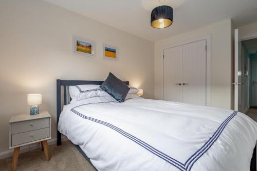 a bedroom with a large white bed and a night stand at Dreelside Escape - No 15 in Anstruther