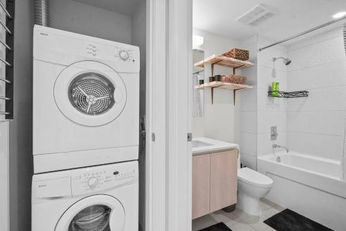 een witte wasmachine en droger in de badkamer bij Downtown Calgary Modern 1BR with Pullout couch in Calgary