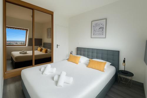 ein Schlafzimmer mit einem großen weißen Bett und einem Spiegel in der Unterkunft Bel appartement Vue Mer Climatisé à Biarritz in Biarritz