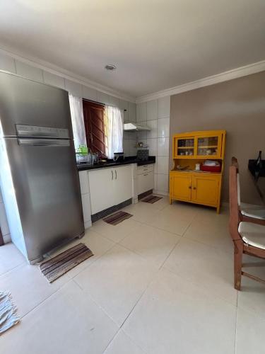 a kitchen with a stainless steel refrigerator and a yellow cabinet at Casa Duplex praia de Ubu in Anchieta
