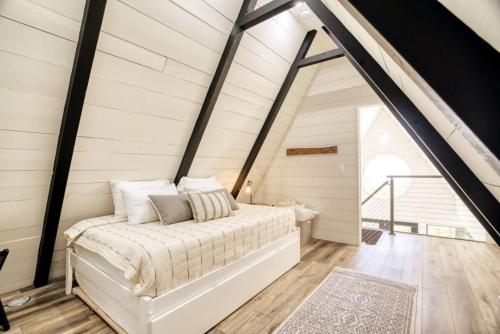 a bedroom with a white bed in a attic at The Black Aframe - HOT TUB and Mountain Views in Evergreen Farms