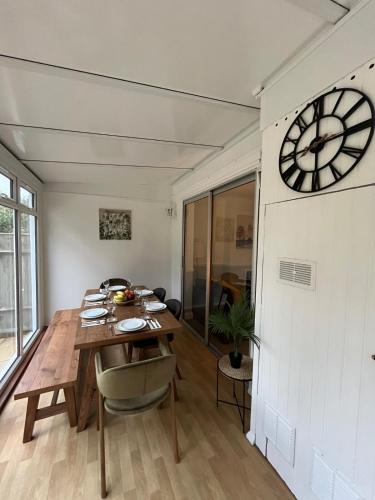 a dining room with a table and a clock on the wall at Pitfold Road in London