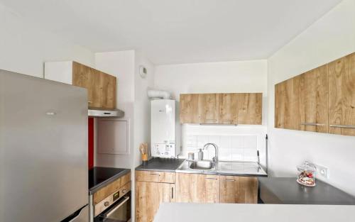 a kitchen with wooden cabinets and stainless steel appliances at Cocon avec petit jardin centre Bondy in Bondy