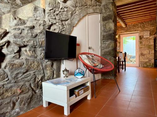 a living room with a tv on a stone wall at Haven Azores in Faial da Terra