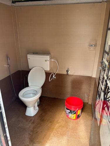a bathroom with a toilet and a red bucket at Mystic Valley Vattavada in Kottakamboor