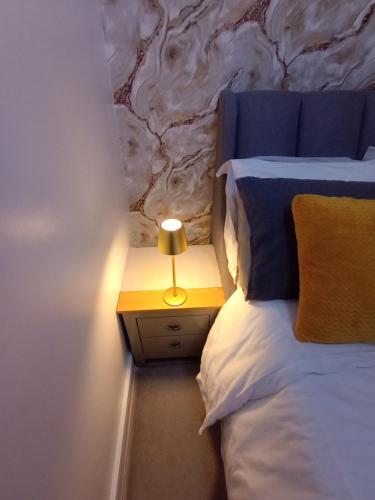 a bedroom with a bed and a night stand with a lamp at Bavelle Bilston Urban Village in Bilston