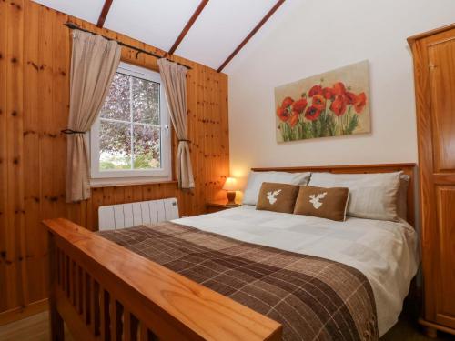 a bedroom with a bed in a room with a window at The Log Cabin in Gloucester