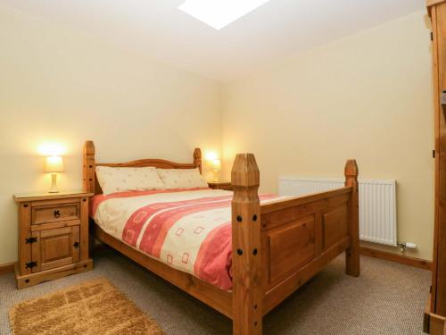 een slaapkamer met een houten bed en 2 nachtkastjes bij Orchard Cottage in Hartpury