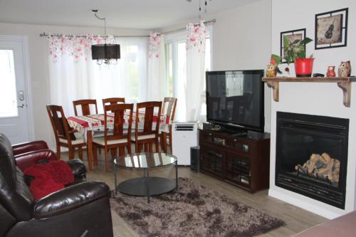 a living room with a fireplace and a dining room at Le Gîte du Pêcheur in Metabetchouan