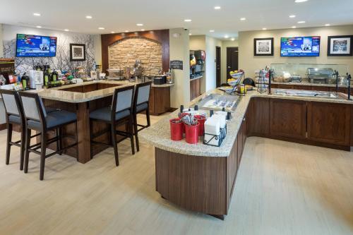 a restaurant with a bar with chairs and a counter at Staybridge Suites Omaha West by IHG in Omaha