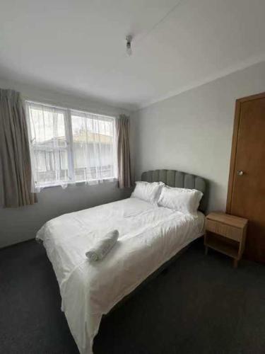 a bedroom with a large white bed and a window at 3 bedrooms House,77 Slacks Rd in Palmerston North