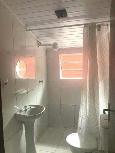 a white bathroom with a sink and a toilet at Chalé Damata in Ubatuba