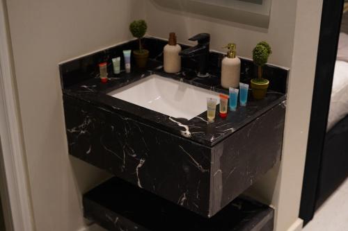 a bathroom with a black marble sink with bottles and candles at Alsultan Cozy Studio in Al Khobar