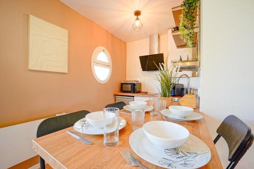 a dining room table with bowls and plates on it at Le Cocon à 15 minutes de Disneyland Paris in Bussy-Saint-Georges