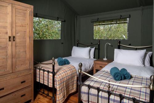 TalybontにあるBwncath Glamping Lodgeのベッドが2つと窓が2つある寝室