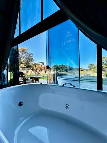 a bath tub in a room with a large window at Cabana Pehuen in Santa Maria do Erval