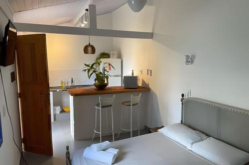 a bedroom with a bed and a kitchen with a counter at Chalé no Itaguá, ao lado do aquário de Ubatuba in Ubatuba