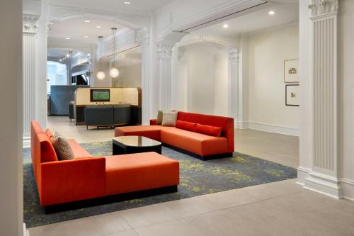 a living room with two orange couches and a table at Courtyard by Marriott New Orleans French Quarter/Iberville in New Orleans