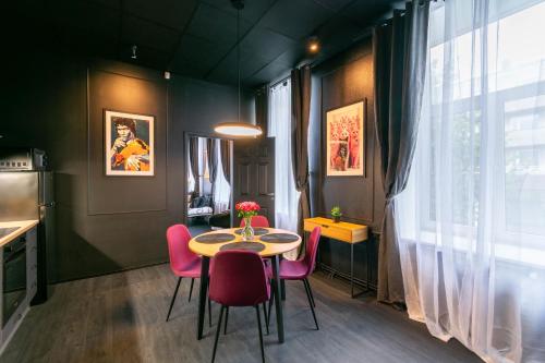 een eetkamer met een tafel en roze stoelen bij Apartments24 Black 1903 in Rakvere