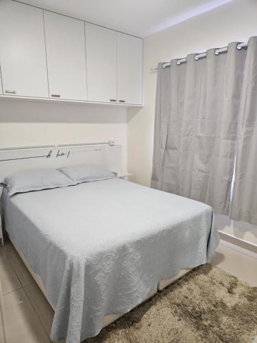 een witte slaapkamer met een bed en een raam bij Loft encantador próximo a Roda Gigante,excelente localização com ar condicionado in Balneário Camboriú