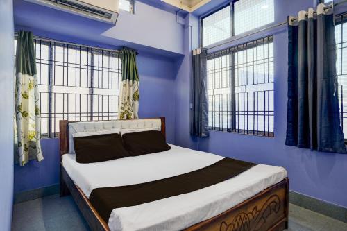 a bedroom with a bed with blue walls and windows at Hotel O Dream Lodge in Nowgong