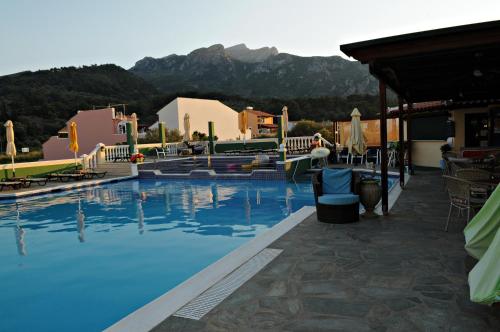 a hotel swimming pool with a mountain in the background at Hotel Athena in Kokkari
