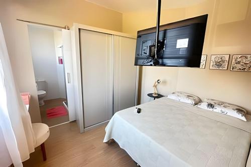 a bedroom with a white bed and a flat screen tv at Mario401| Loft in Leblon next do Lagoa in Rio de Janeiro