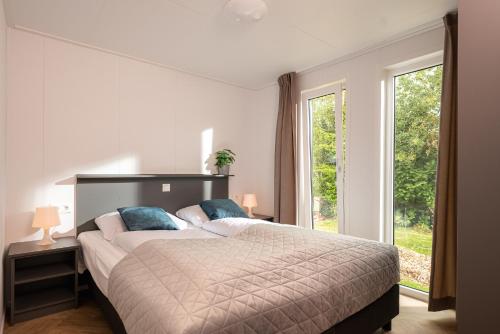 a bedroom with a large bed and a large window at Slow Living bij Mölke x Wellnesslodges in Zuna