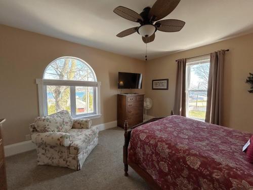 a bedroom with a bed and a chair and a ceiling fan at Lady Mary Angeline in Saint Ignace