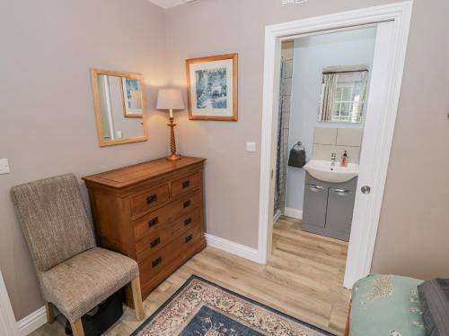 a bedroom with a dresser and a sink and a chair at Rose Stables in Carterton