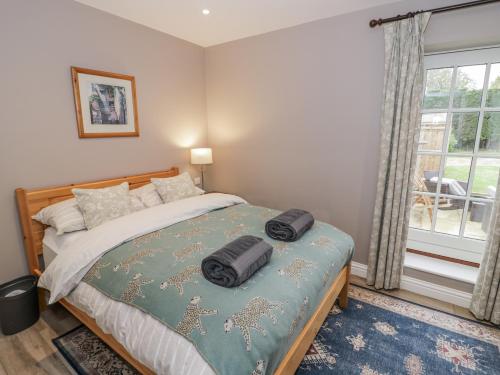 a bedroom with a bed with two bags on it at Rose Stables in Carterton