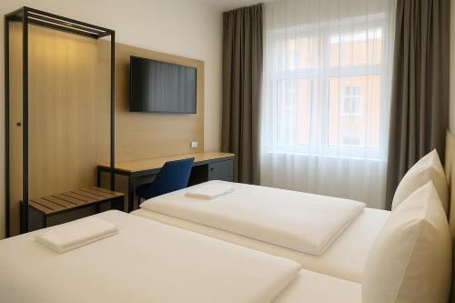 a hotel room with two beds and a television at HI Grand City Hotel in Hannover