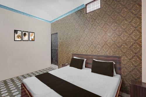 a bedroom with a bed and a wall at Hotel O Shubh Inn in Jhānsi