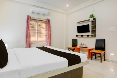 a bedroom with a bed and a desk and a television at HOTEL O AADRITI RESIDENCY in Bhubaneshwar