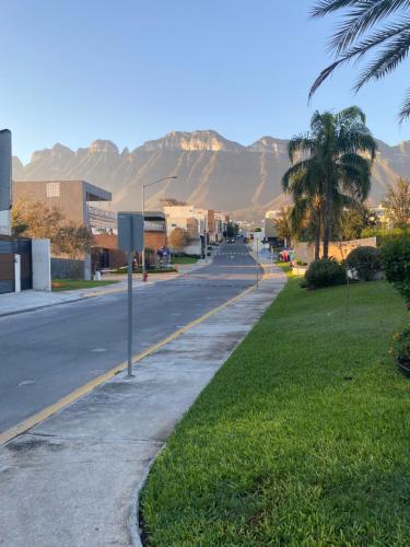 an empty street with palm trees and mountains in the background at Cozy Room in Monterrey