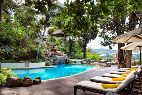 a pool at a resort with lounge chairs and umbrellas at Centara Villas Phuket in Karon Beach