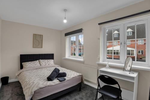ein Schlafzimmer mit einem Bett, einem Schreibtisch und Fenstern in der Unterkunft Luxury 2-Bedroom Home 10 Minutes from Birmingham City Centre in Birmingham