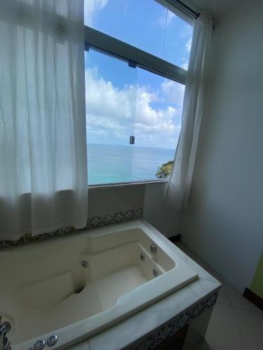a bath tub in a bathroom with a large window at Apartamento no Corredor da Vitoria in Salvador
