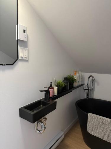 a bathroom with a black sink and a bath tub at Hebergement du grenier 2 0 in Notre-Dame-des-Monts