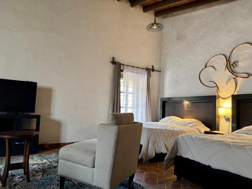 a bedroom with two beds and a chair and a television at Galera centro de Tepoztlan in Tepoztlán