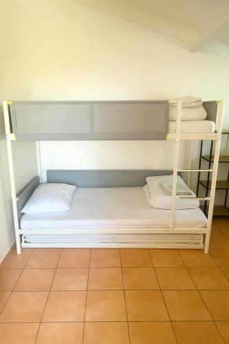 a bunk bed with white sheets and pillows on it at Vakantiehuisje Wenduine in De Haan