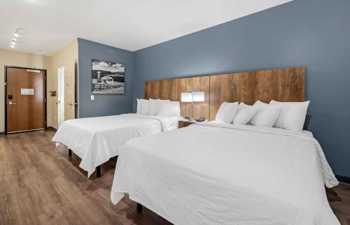 2 Betten in einem Zimmer mit blauen Wänden und Holzböden in der Unterkunft Extended Stay America Premier Suites - Nashville - Smyrna in Smyrna