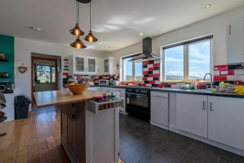 a large kitchen with white cabinets and a wooden counter top at Burnside Cottage & Caravan Woodend in Portree