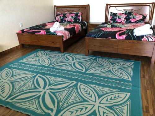 two beds in a room with a rug on the floor at Samoa FINAU 685 Accomodations in Vaitele
