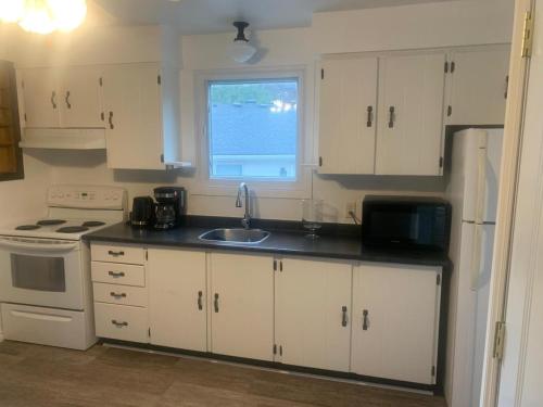 een keuken met witte kasten, een gootsteen en een raam bij Napaeno's Place - Home Away from Home in Kingston