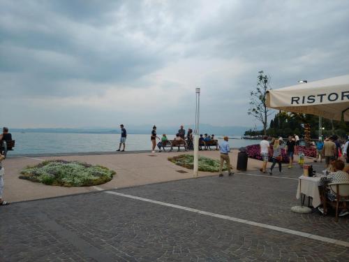 Un grupo de personas caminando por una acera cerca del agua. en Eli's House in Bardolino sul Garda, en Bardolino