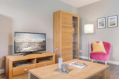 a living room with a television on a wooden entertainment center at Inselhuus Fehmarn 2 in Petersdorf auf Fehmarn